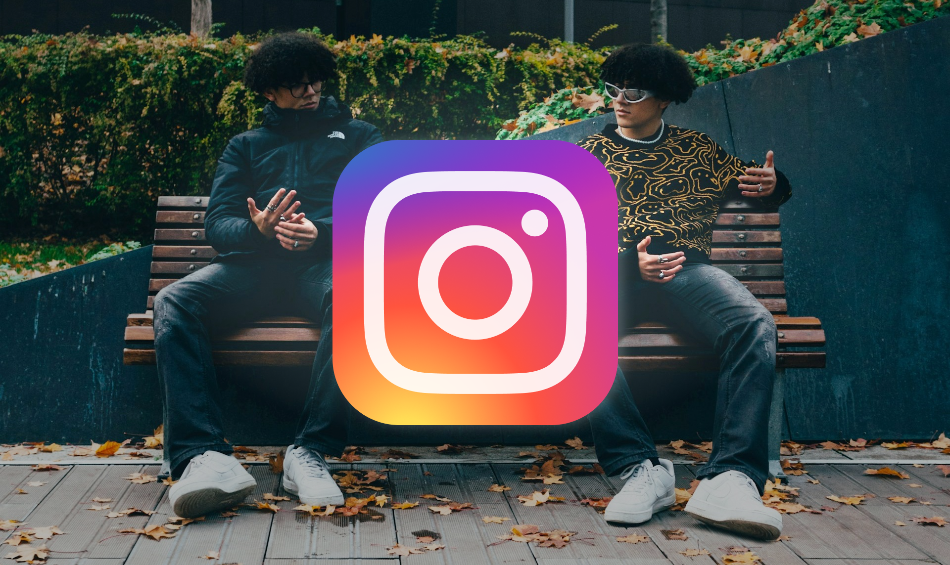 Two identical individuals sitting side-by-side on a bench with their faces obscured by a large Instagram logo icon